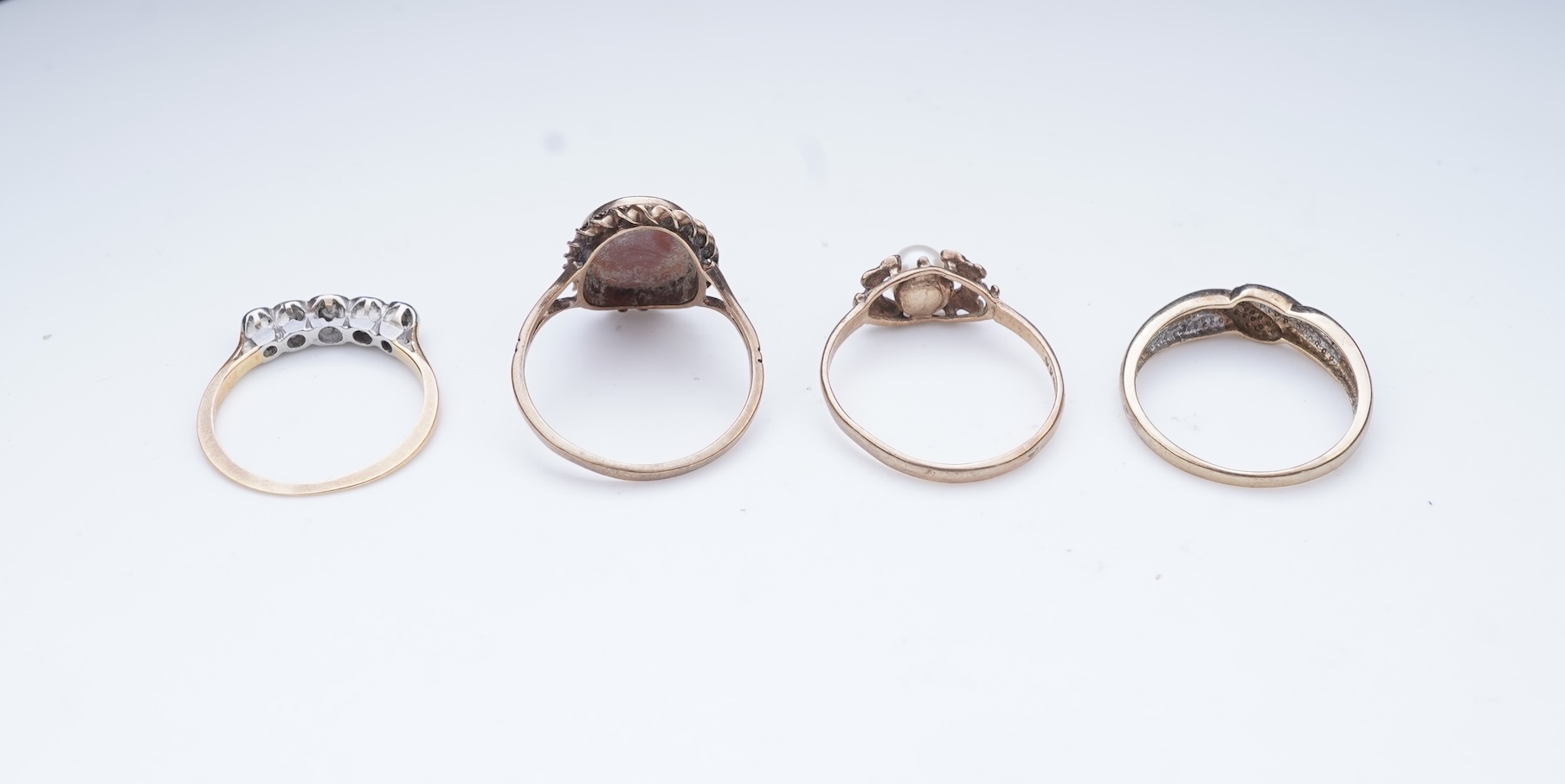 A collection of four rings and a pendant